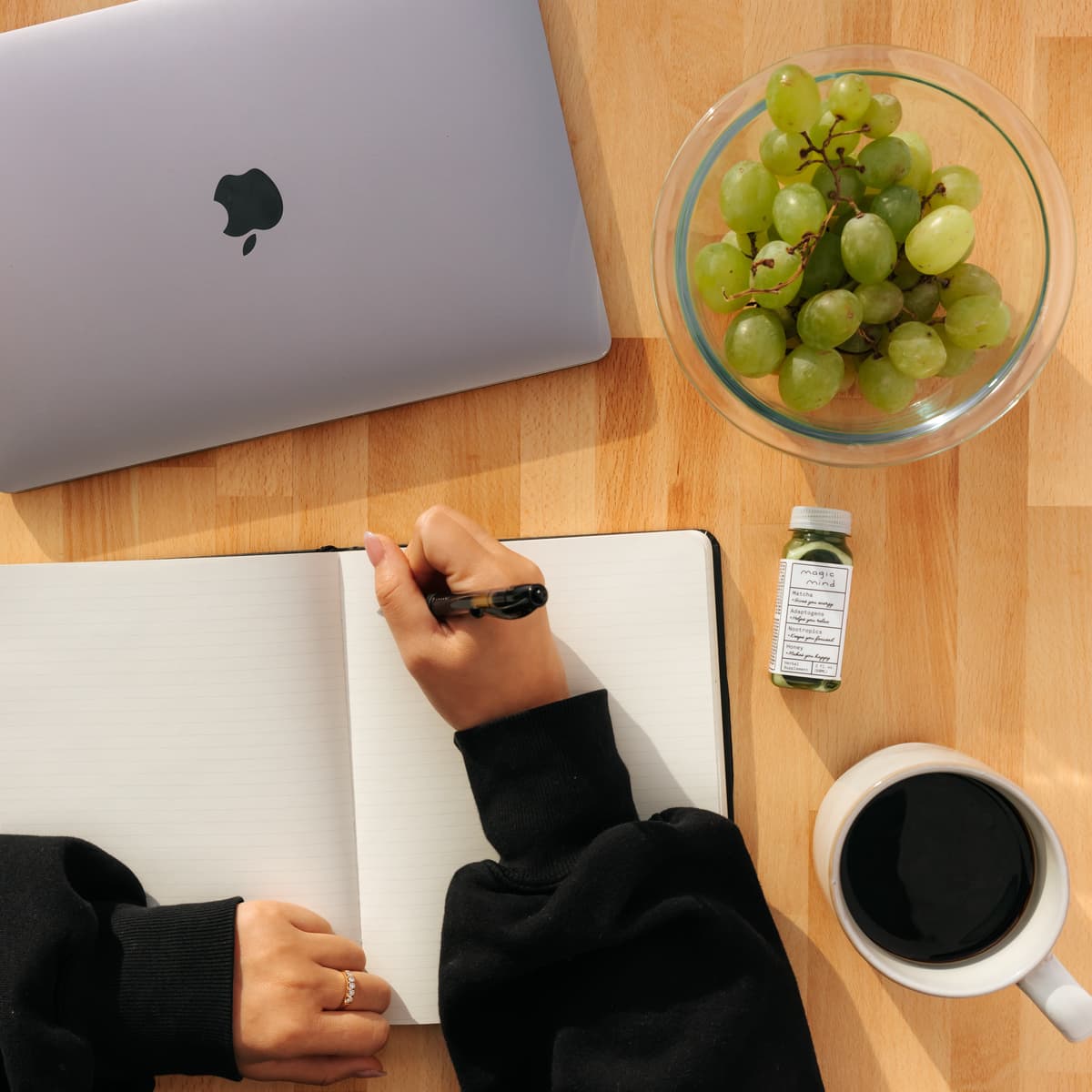 Person writing in journal with healthy foods and supplements on table